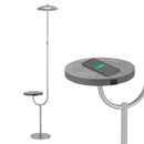 Modern grey floor lamp featuring a wireless charging station and a built-in table top shelf, surrounded by various electronic devices and gadgets.