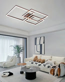 Modern artistic design geometric aluminum pendant light with LED technology, hanging above a grey couch in a well-lit interior featuring wooden accents and a large window.