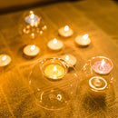 Amber-colored glass candle holder designed for votive or tealight candles, showcasing a circular shape with visible wax and a gentle light illuminating the surrounding area.