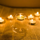 Amber-colored glass candle holder with a tealight candle lit inside, casting a warm glow.