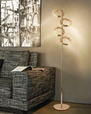 Gold diamond-patterned adjustable angles floor lamp in a stylish interior with wooden elements, chair, table, and decorative twigs.