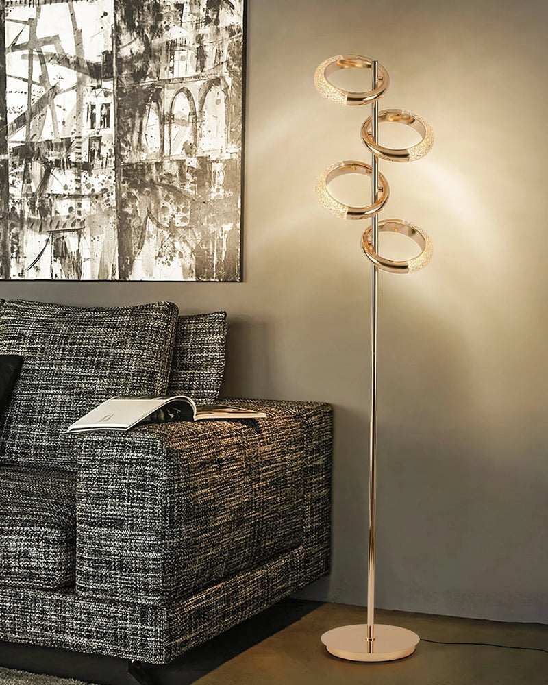 Gold diamond-patterned adjustable angles floor lamp in a stylish interior with wooden elements, chair, table, and decorative twigs.