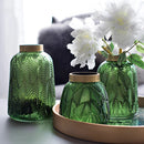 Green glass vase designed for hydroponic plants featuring a Nordic design, filled with flowers and greenery.