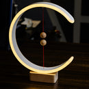 A modern interior lamp featuring a crescent-shaped glow, designed with magnetic switches, composed of wood and metal elements, and artistically presented with circular and rectangular shapes in a still life photography setting.