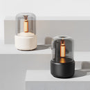 LED aromatherapy diffuser with a candle light effect, featuring a cylindrical shape made of composite materials, with elements of wood and metal, displayed on shelving in an interior setting.
