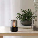 LED aromatherapy diffuser with a candle light effect, displayed in an interior setting with houseplants and wooden decorations.