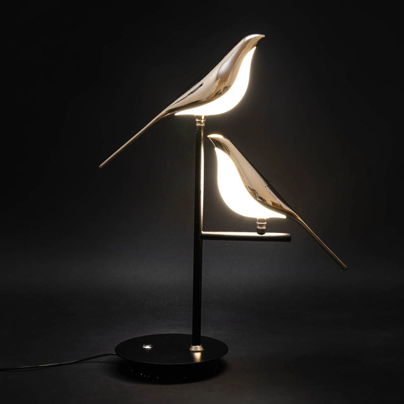 Postmodern LED desk lamp featuring a galvanized golden bird design, with a metal beak and glass elements, displayed against a dark background.