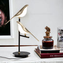 LED desk lamp featuring a postmodern design with a galvanized golden bird, crafted from a combination of wood and metal materials.