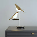 Artistic LED desk lamp featuring a postmodern galvanized golden bird design, crafted from metal and plywood, with a seabird sculpture balanced at the base.