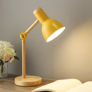 Yellow LED desk lamp featuring a Scandinavian minimalist design with a three-color switch, displayed on a wooden table alongside a vase with roses and other plants.