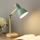 Green LED desk lamp featuring a Scandinavian minimalist design with a switch, displayed on a wooden table next to a vase with flowers and a small plant.