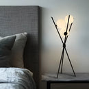 Modern black LED Moonlamp table lamp on a wooden floor, featuring a grey pillow for a comfortable and artistic touch in a living room setting.