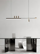 Sleek LED pendant light with a Nordic-inspired design, hanging over a grey desk and chair set in a room with artistic wall elements.