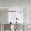 Sleek Nordic-inspired LED pendant light hanging over a modern dining table with wooden chairs in an interior setting.