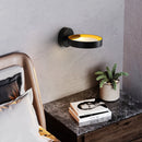 Contemporary iron and acrylic LED wall light with artistic design, displayed in a living room setting with houseplants, a flowerpot, and wooden grey flooring.