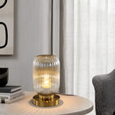 Crystal table lamp on a wooden table with a metal base, illuminated in a room featuring curtains and elegant interior design elements.