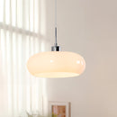 Modern Jaxon glass pendant light featuring LED bulbs, suspended from a wooden ceiling fixture with hardwood flooring visible below.