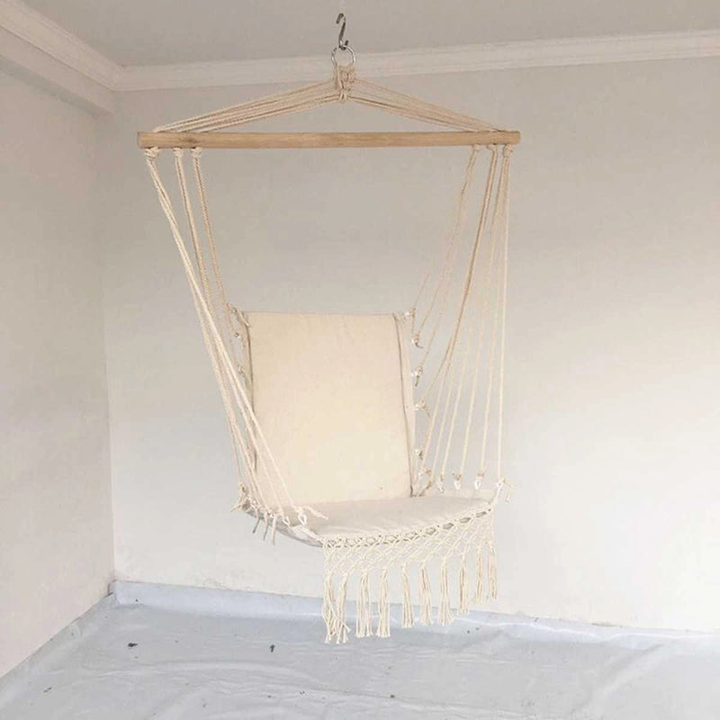 Macramé hammock swing made of natural materials, suspended from a ceiling with a light fixture visible above and glass elements in the background.