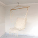 Artistic macramé hammock swing hanging from a wooden ceiling, surrounded by sculptures and glass elements, suitable for garden settings.