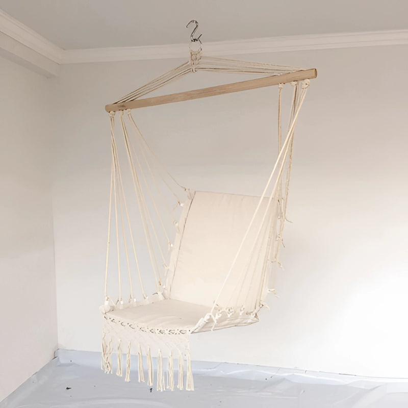 Artistic macramé hammock swing hanging from a wooden ceiling, surrounded by sculptures and glass elements, suitable for garden settings.