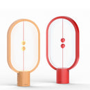 Magnetic Balance Table Lamp with LED Lighting featuring a rectangular wood base and a circular magenta light element with artistic graphics.