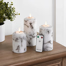 Set of three marble-patterned LED flameless candles displayed with houseplants and wooden decor elements.