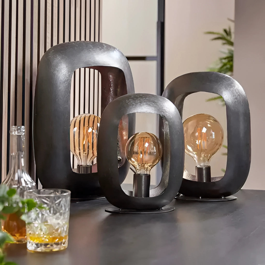 Vintage style metal table lamps with intricate designs, featuring elements of wood and glass, set in a cozy environment adorned with plants.
