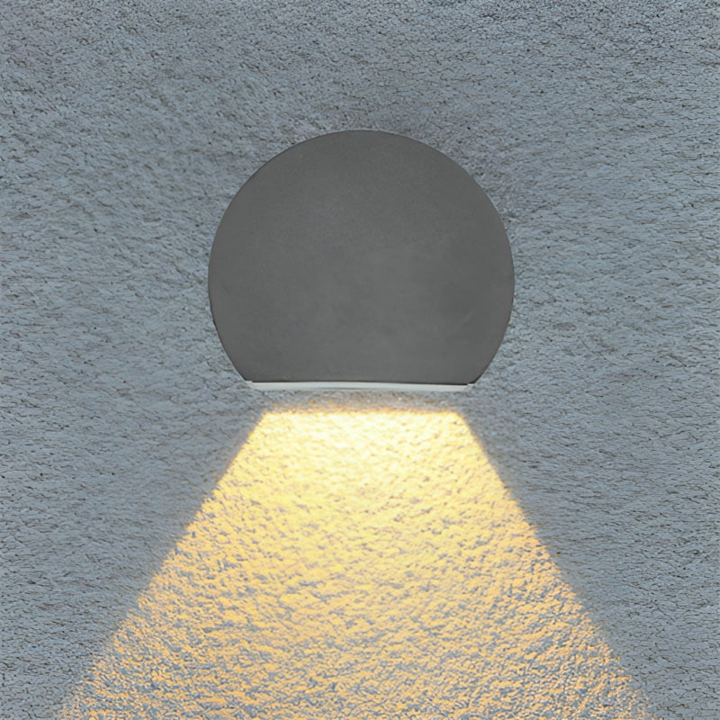 Modern LED wall sconce in sand black and grey, featuring a symmetrical pattern with circular and rectangular elements, and crafted from aluminum and borosilicate glass. The design includes artful shadows and tints of electric blue.