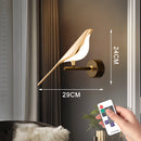 Gold modern rotatable wall sconce with a 360-degree lampshade, featuring a gesture-controlled remote for warm light, mounted next to a wooden door.