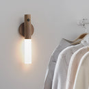 Motion Sensor LED Rechargeable Night Light with a wooden design mounted on a ceiling, emitting a soft glow, surrounded by a rectangular frame, with elements resembling clothes hangers and formal wear in the background.