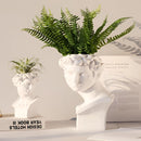 Greek head-shaped resin vase adorned with a leafy houseplant, styled as both a decorative art piece and functional planter.