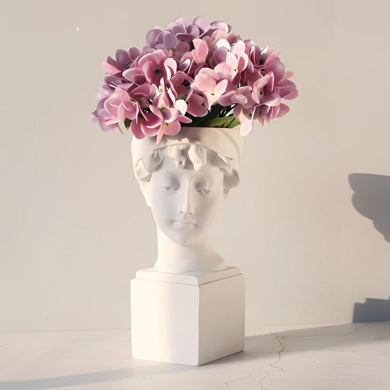 Neoclassical Greek head resin vase used as a planter, filled with a variety of houseplants and artificial flowers, displaying detailed petals and arranged beautifully.