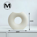 Nordic style ceramic donut vase in a modern circular design, displayed against a plain wall, emphasizing its sleek and minimalist aesthetic.