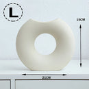 Nordic style ceramic donut vase featuring a modern circular design displayed in an office or living room setting with artistic wall and ceiling details.