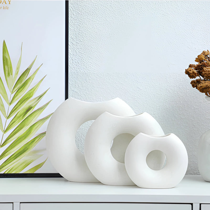 Nordic style ceramic donut vase featuring a modern circular design, displayed in an office or living room setting, complemented by plants and artistic interior elements.