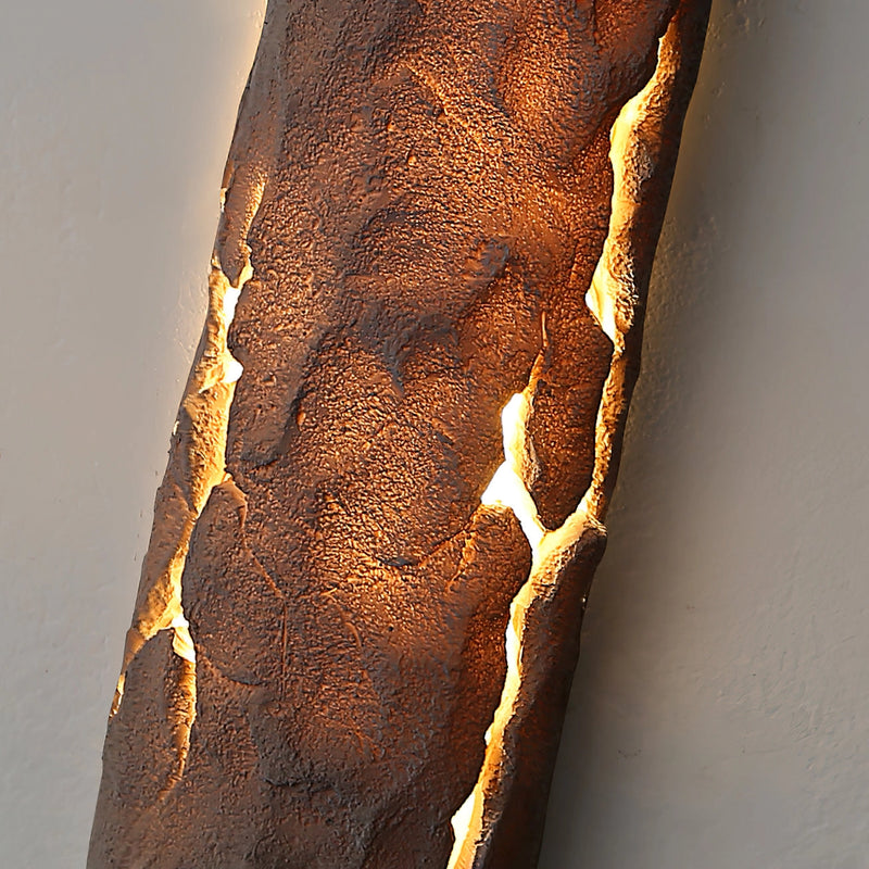 Outdoor wall light featuring IP65 waterproof rating with a premium resin faux rock finish, designed to resemble a sculpture with amber tints and shades.