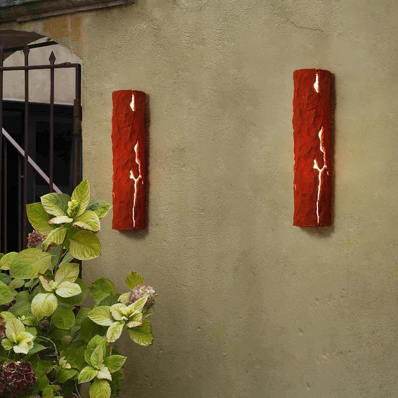 Outdoor wall light with IP65 waterproof rating, featuring a premium resin faux rock finish, installed next to a window, surrounded by plants in flowerpots, enhancing the building's facade.