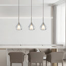Nordic style pendant lamp featuring a clear raindrop design with starlight effect, displayed over a white wooden table and chairs, enhancing the minimalist interior design.