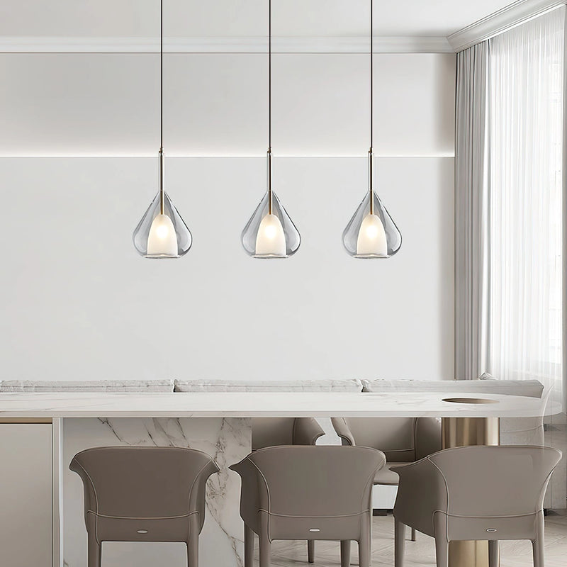 Nordic style pendant lamp featuring a clear raindrop design with starlight effect, displayed over a white wooden table and chairs, enhancing the minimalist interior design.