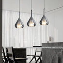 Nordic style pendant lamp featuring a clear raindrop design with starlight effect, displayed in a monochrome interior with wood accents, a grey chair, and a table.
