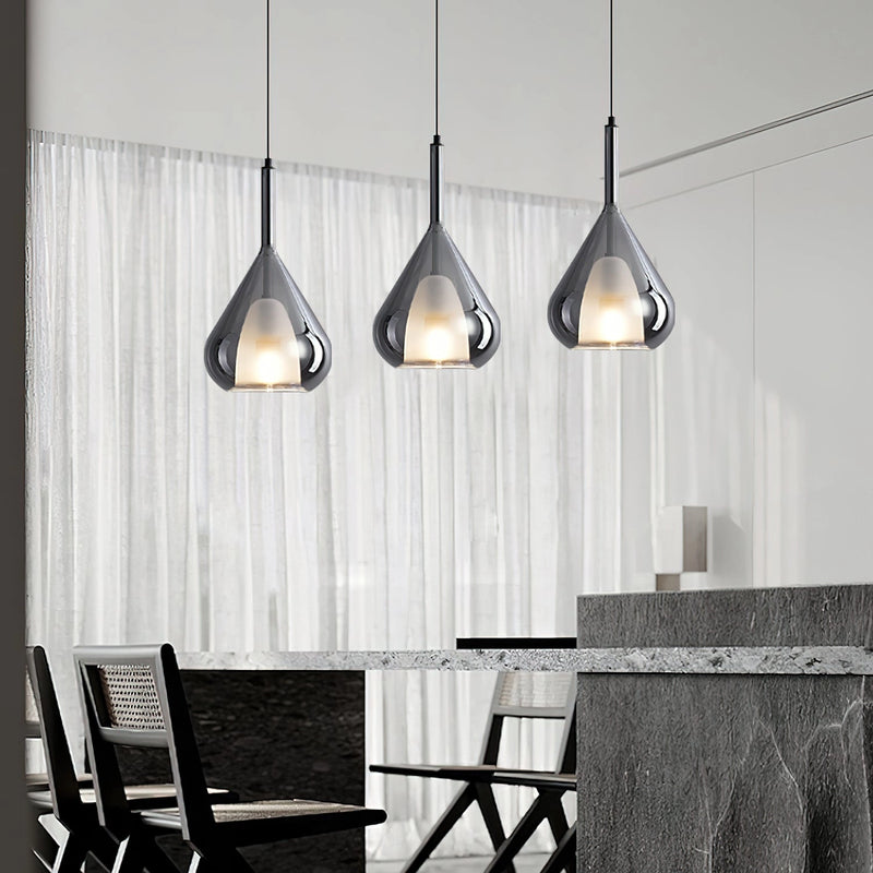 Nordic style pendant lamp featuring a clear raindrop design with starlight effect, displayed in a monochrome interior with wood accents, a grey chair, and a table.