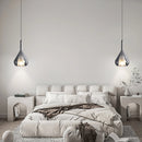 Nordic style pendant lamp featuring a clear raindrop design with a starlight effect, suspended in a room with white and black decor and wooden elements.