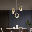 Modern Dante pendant lamp chandelier displayed in a stylish interior setting with wood furniture, a table, chairs, and a plant near a window, showcasing both the lamp's design and the room's architecture.