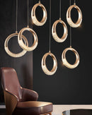 Modern Dante pendant lamp featuring a gold chandelier design, displayed above a brown couch in a setting with wooden accents.