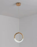 Modern Pendant Lamp Dante chandelier featuring a combination of wood and metal, with circular and rectangular elements, designed to resemble body jewelry, hanging from the ceiling.