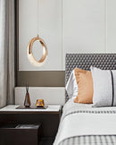 Modern chandelier Pendant Lamp Dante featuring a rectangular design with wood and mirror elements, placed in an interior setting with grey tones and furniture including a bed frame and pillows.