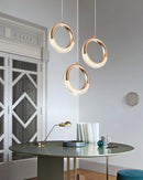 Modern Dante pendant lamp chandelier displayed over a rectangular wooden table, illuminating a room with white walls and architectural details.