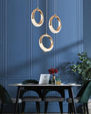 Modern Dante pendant lamp chandelier displayed in a stylishly decorated interior with a table, chairs, and a laptop, complemented by natural lighting from a window and indoor plants.