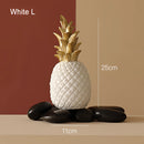 Golden resin pineapple-shaped ornament in Nordic style for home decor, displayed against a wooden background with plants and natural elements around.