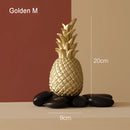 Golden resin ornament in the shape of a medium-sized pineapple, designed for Nordic home decor, displayed in a flowerpot.